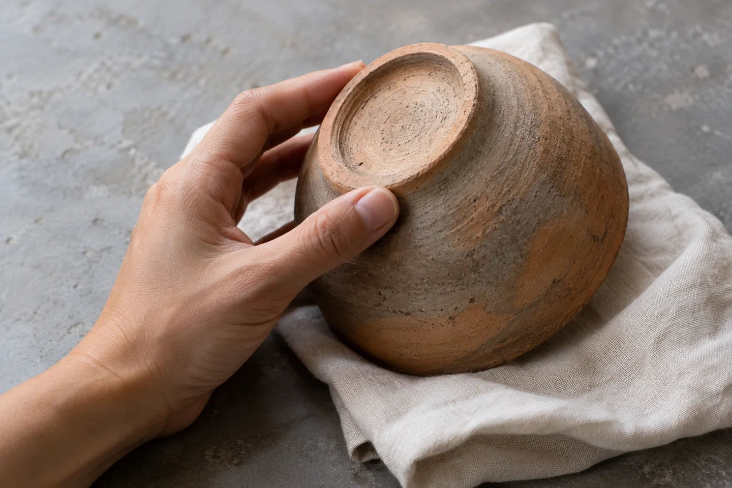 Una mano revisa la base de un cuenco artesanal